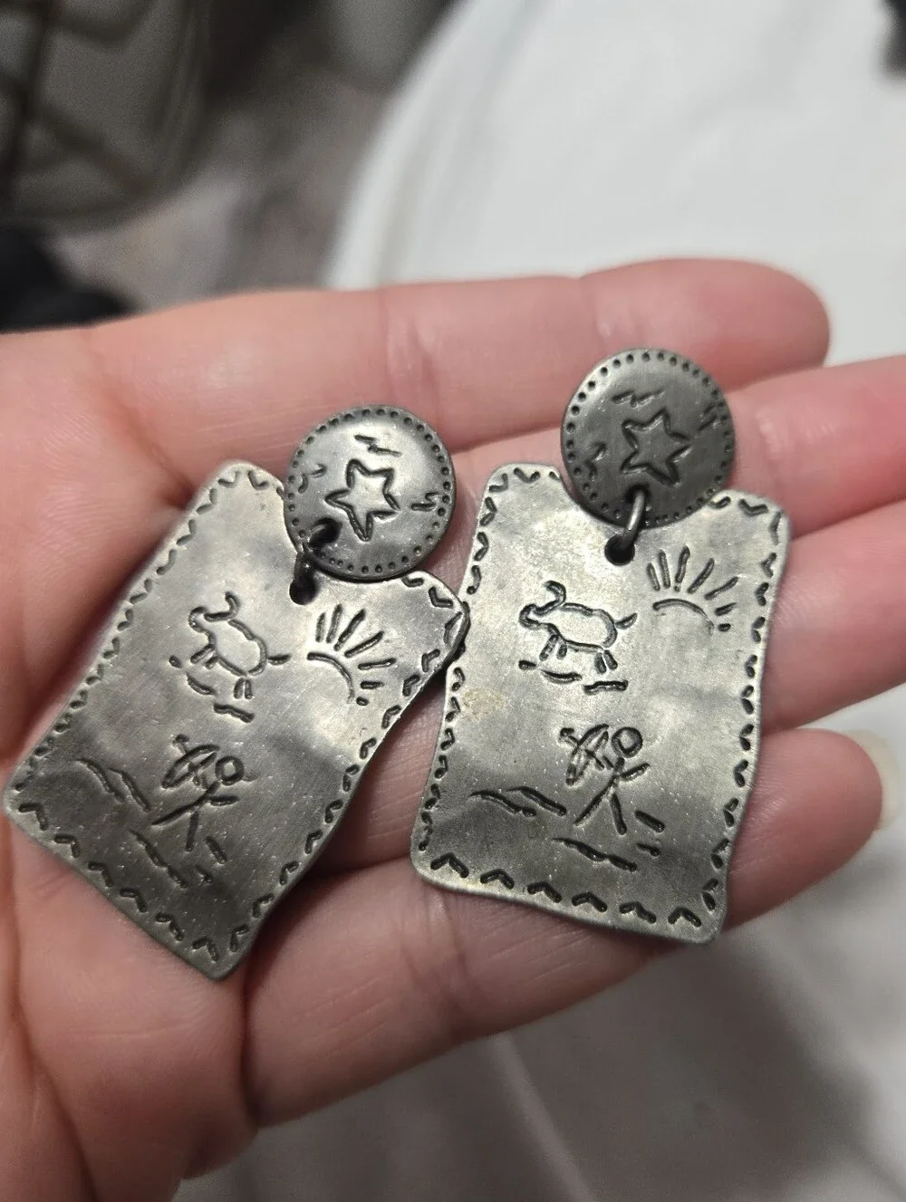 Vintage silver-tone drop earrings featuring embossed Southwestern petroglyph